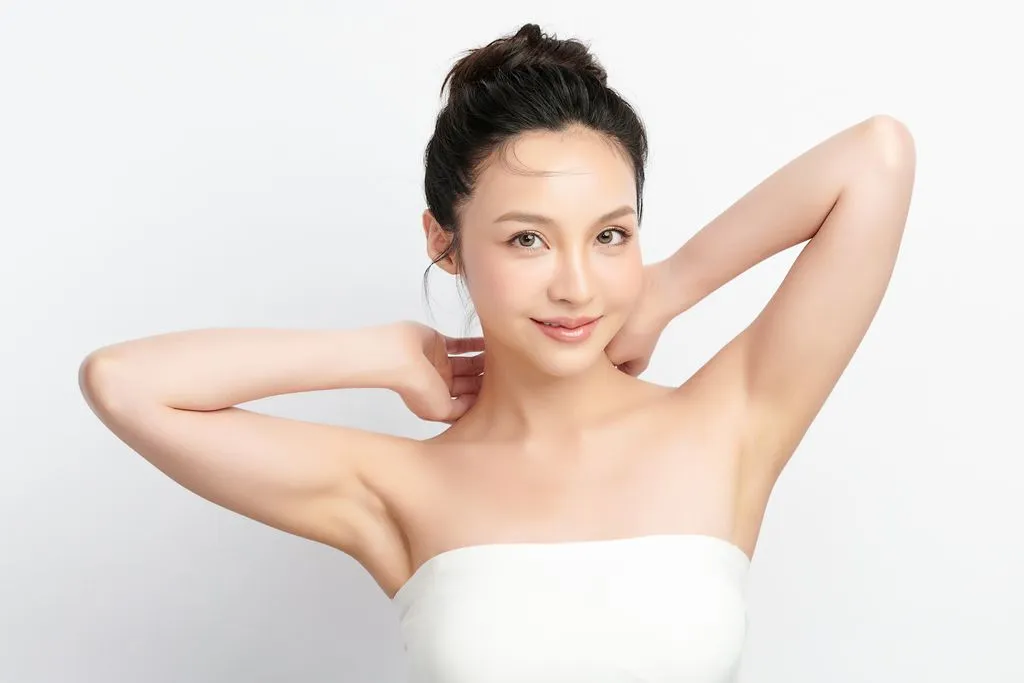 Smiling woman with arms raised, wearing strapless top.