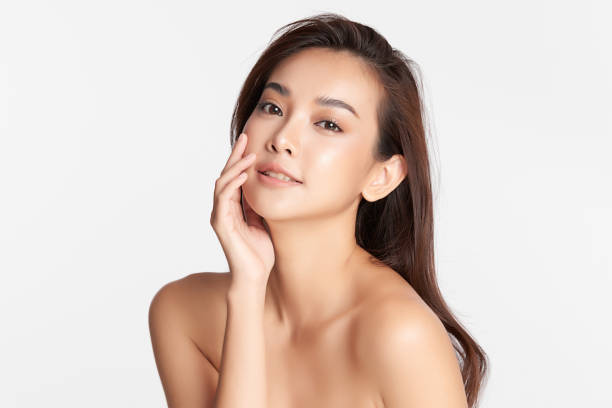 Smiling woman touching her face, white background.