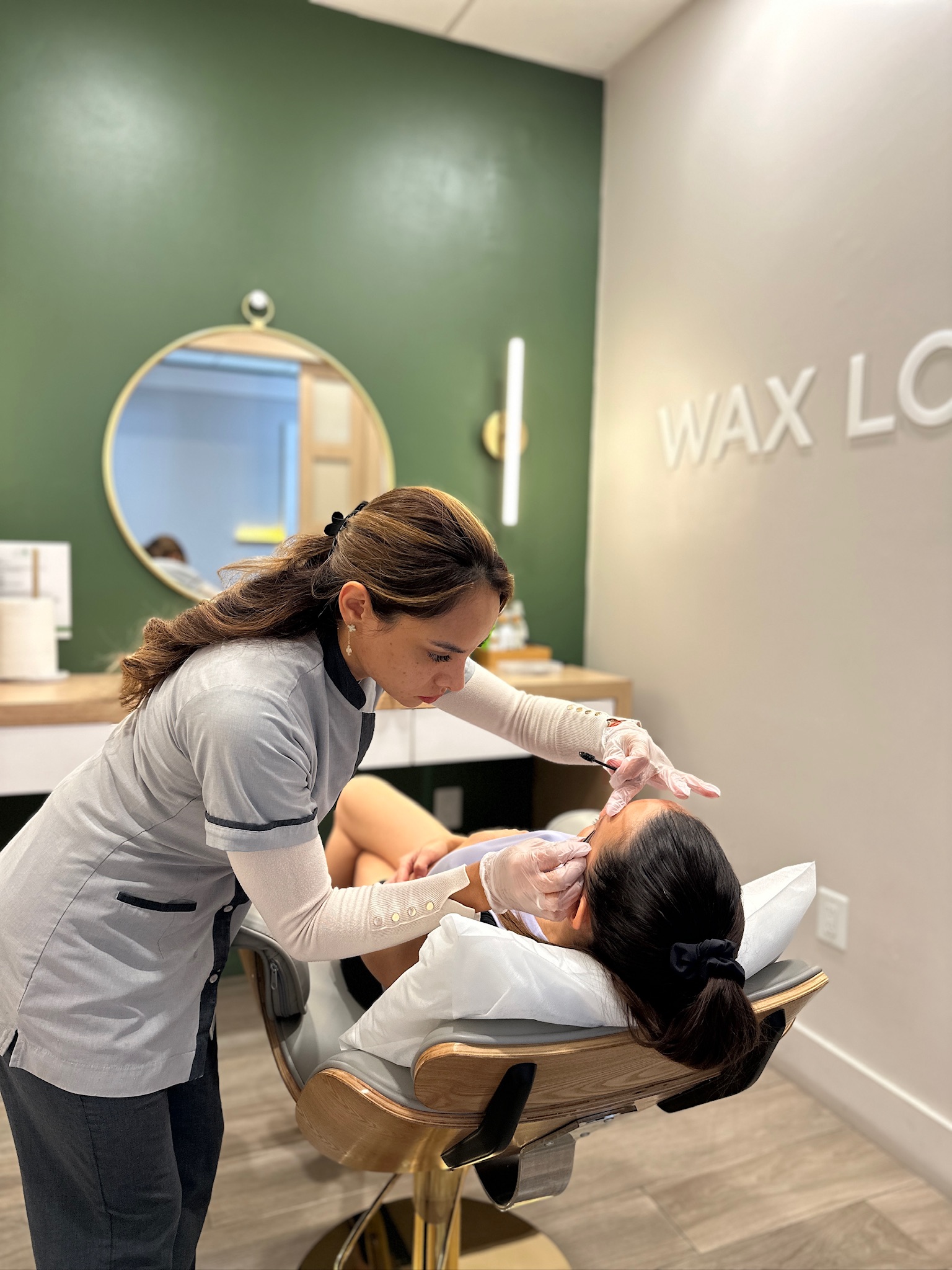 Beautician waxing client's eyebrows in salon.