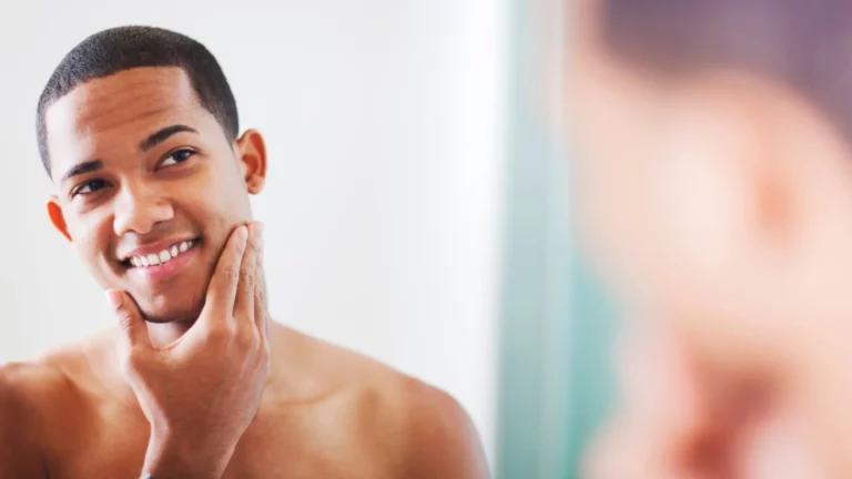 Man checking skin in mirror, smiling